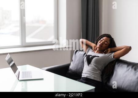 Heureuse étudiante de travailleuse africaine détendue satisfaite de l'étude de travail terminée sur le lieu de travail Banque D'Images