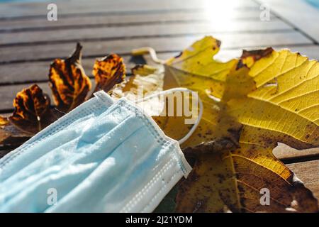 Le masque médical repose sur les feuilles jaunes d'automne covid Banque D'Images