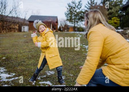 Garçon avec le syndrome de Down avec sa mère jouant avec la neige dans le jardin. Banque D'Images