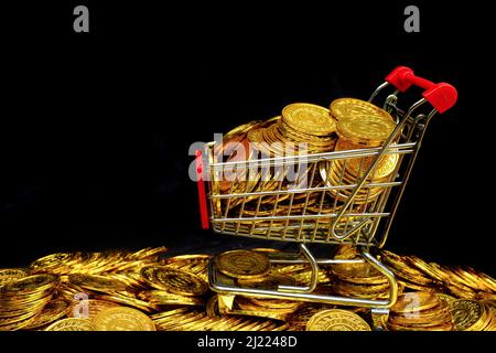 Pièce d'or dans le panier sur un empilage de pièces d'or sur fond noir Banque D'Images