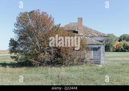 Un bâtiment de maison d'école de pièce par une route sur la prairie. Banque D'Images