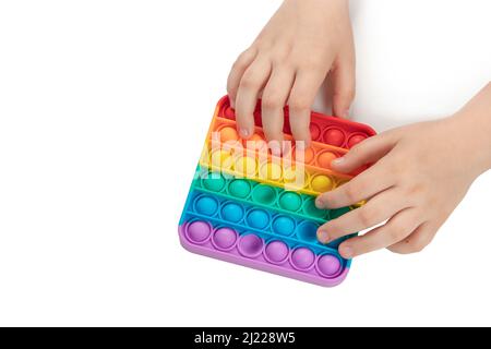 Enfant jouant avec l'arc-en-ciel pop il, appuyant les bulles avec ses doigts, vue de dessus.Nouveau jouet antistress pour les enfants et l'adulte. Copier l'espace pour le texte ou de Banque D'Images