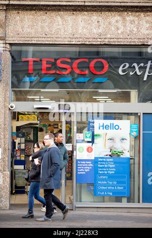 Les gens quittent et entrent dans un magasin Tesco dans le centre de Londres après l'entrée en vigueur des règles du plan B Covid-19. Banque D'Images