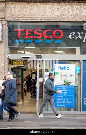 Les gens quittent et entrent dans un magasin Tesco dans le centre de Londres après l'entrée en vigueur des règles du plan B Covid-19. Banque D'Images