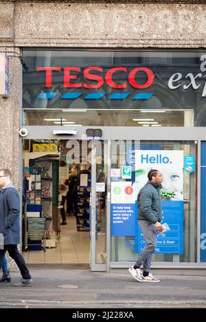 Les gens quittent et entrent dans un magasin Tesco dans le centre de Londres après l'entrée en vigueur des règles du plan B Covid-19. Banque D'Images