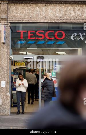 Les gens quittent et entrent dans un magasin Tesco dans le centre de Londres après l'entrée en vigueur des règles du plan B Covid-19. Banque D'Images