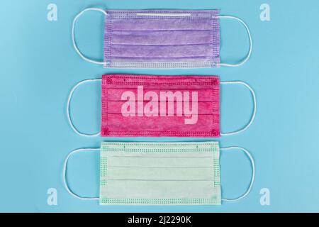 Masques médicaux de différentes couleurs sur fond bleu. Banque D'Images
