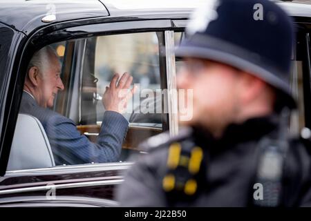 Alors qu'un policier rencontré regarde, le prince Charles, le prince de Galles, se délasse devant les spectateurs lorsqu'il arrive à l'abbaye de Westminster pour le service commémoratif à son père, le duc d'Édimbourg, le 29th mars 2022, à Londres, en Angleterre. Banque D'Images