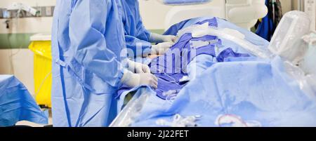 Deux médecins chirurgiens non-descript effectuant une chirurgie dans une salle chirurgicale portant des exfoliants bleus et des gants en latex blanc Banque D'Images