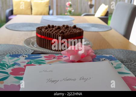 Carte de fête des mères, cadeau et gâteau sur une table Banque D'Images