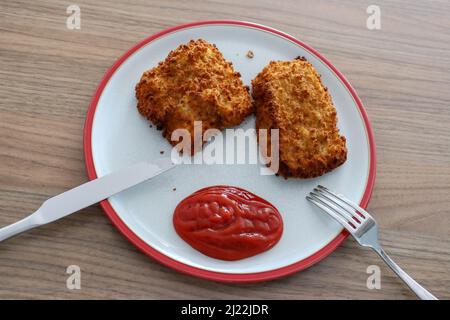 Steaks de morue panés sur une assiette avec sauce tomate Banque D'Images