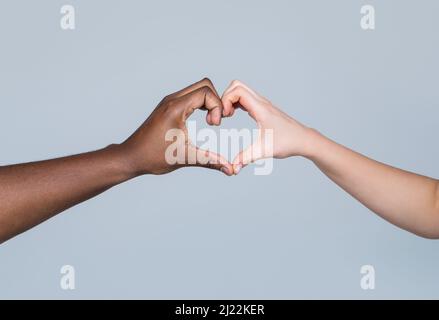 Les gens de différentes couleurs de peau mettent leurs mains ensemble faisant la forme de coeur dans le fond blanc. La charité, l'amour et la diversité - gros plan de femme et d'homme Banque D'Images