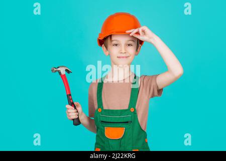 Enfant habillé comme un ouvrier de construction. Petit garçon portant un casque. Portrait petit constructeur en casque marteau. Casque de construction pour enfants, casque de chantier. Marteau Banque D'Images