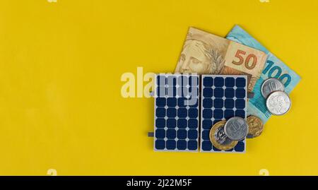Panneau photovoltaïque, argent et fil de fiche isolé sur fond jaune. panneau olar avec des valeurs variées de l'argent brésilien. Bus alternatif d'énergie propre Banque D'Images