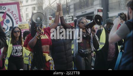 Londres, Royaume-Uni - 03 19 2022: Deux femmes noires protestataires sur Regent Street tenant les mains levées marchant avec des mégaphones, pour le "monarque contre le racisme". Banque D'Images