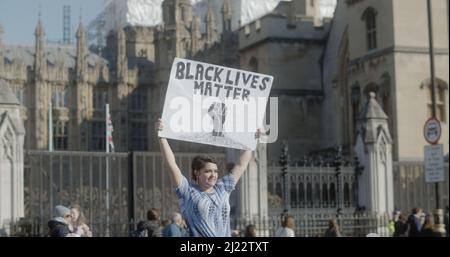Londres, Royaume-Uni - 03 19 2022: Une femme portant un panneau sur la place du Parlement, «Black Lives Matter», pour l'année «la marche contre le racisme». Banque D'Images