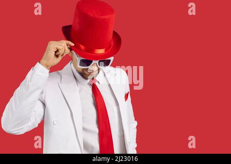 Portrait d'un beau gentleman en costume blanc, chapeau rouge et lunettes sur fond d'espace de copie Banque D'Images