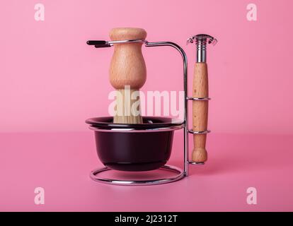 Kit de rasage pour homme, rasoir, brosse, tasse pour mousse dans un style rétro vintage. Tondeuse multistyles sur fond rose. Concept d'hygiène et de soin du visage. Banque D'Images