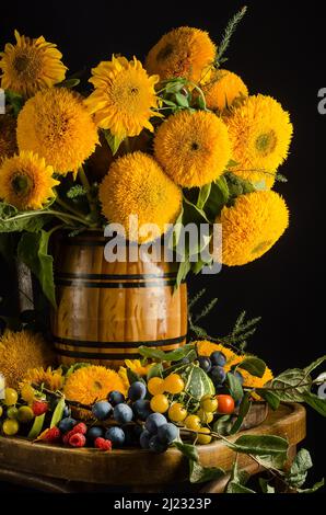 Encore la vie de beaux tournesols décoratifs dans un vase sur une chaise sur fond noir avec l'effet du grain de film Banque D'Images