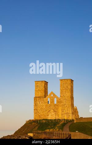 Les tours jumelles de l'église en ruines de Sainte Marie à Reculver, éclairées par le soleil couchant. Kent, Angleterre. Banque D'Images