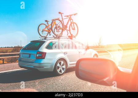 Support de montage sur toit pour vélo. Transport de VTT sur le toit de la voiture. Voiture avec deux vélos montés sur le toit sur l'autoroute à la journée ensoleillée. Banque D'Images