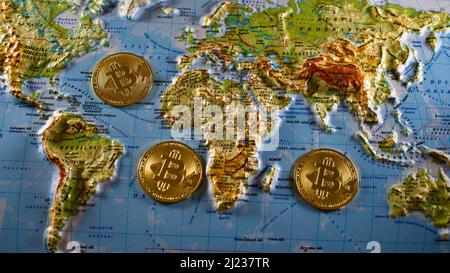 Pièces de bitcoin en métal d'or sur une carte du monde de secours de 3D. Banque D'Images