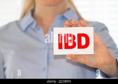 Le médecin tient une carte avec l'abréviation IBD dans ses mains. Banque D'Images