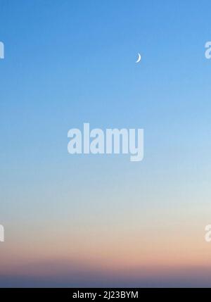 Photographie en couleur du croissant de lune dans le ciel crépuscule Traeth Crigyll à Rhosneigr sur la côte sud de l'île d'Anglesey, au nord du pays de Galles, Royaume-Uni, automne. Banque D'Images