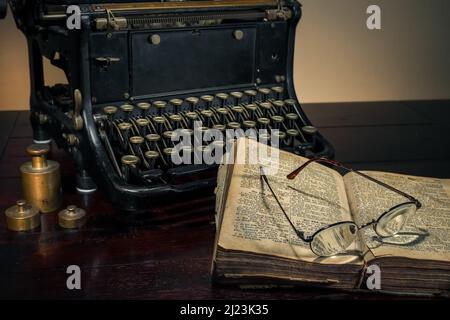 Une machine à écrire vintage sur la table à côté d'un livre ouvert. Banque D'Images