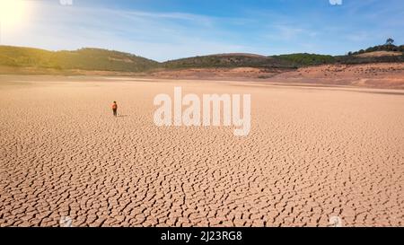 Silhouette d'un homme sur une terre sablonneuse craquée vide non fertile pendant une sécheresse. Le concept de catastrophe écologique sur la planète. Jour ensoleillé Banque D'Images