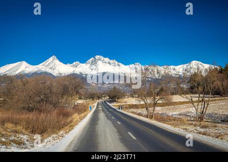 Paysage avec une route menant aux montagnes enneigées. Parc national de High Tatras, Slovaquie, Europe. Banque D'Images