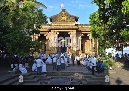 Adorateurs à l'entrée de Kelaniya Raja Maha Vihara, un temple bouddhiste situé dans une banlieue de Colombo Banque D'Images