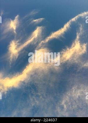 Tourbillon abstrait de nuages de Cirrus ensoleillés contre un ciel bleu profond Banque D'Images