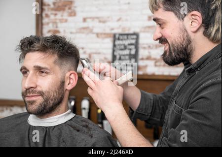 Gros plan de l'homme heureux obtenir une coupe de cheveux, dans le salon de coiffure. Photo de haute qualité. Banque D'Images