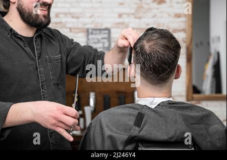 Gros plan de l'homme heureux obtenir une coupe de cheveux, dans le salon de coiffure. Photo de haute qualité. Banque D'Images