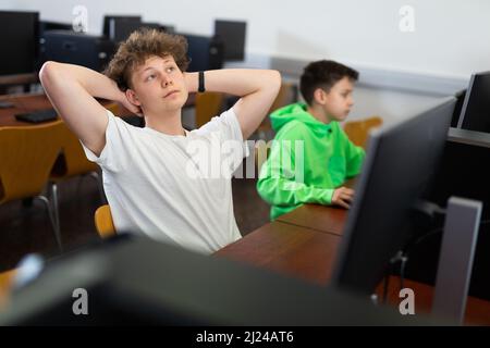 Adolescent se reposant pendant la leçon d'informatique Banque D'Images