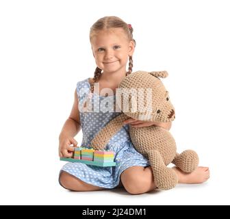 Jolie petite fille avec des blocs de construction et un ours en peluche sur fond blanc Banque D'Images