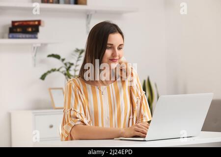 Belle jeune femme avec mignon cobaye travaillant sur ordinateur portable à la maison Banque D'Images