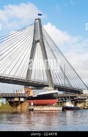 30 mars 2022, Glebe Island Bridge, Sydney, Australie : le navire à vapeur côtier de 1927, John Oxley ayant subi des années de restauration et de préservation, est photographié ici sur le chemin d'être finalement renfloué après 21 ans montés sur un ponton aux ateliers de la Sydney Heritage Fleet à Roselle Bay. Après avoir facilement dégagé l'immense pont ANZAC en béton, le ponton passe par l'ouverture de l'ancien pont Glebe Island sur son chemin vers un quai sec à Garden Island, plus loin en bas du port de Sydney où il sera soigneusement rénové et testé. Banque D'Images