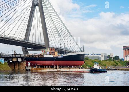 30 mars 2022, Glebe Island Bridge, Sydney, Australie : le navire à vapeur côtier de 1927, John Oxley ayant subi des années de restauration et de préservation, est photographié ici sur le chemin d'être finalement renfloué après 21 ans montés sur un ponton aux ateliers de la Sydney Heritage Fleet à Roselle Bay. Après avoir facilement dégagé l'immense pont ANZAC en béton, le ponton passe par l'ouverture de l'ancien pont Glebe Island sur son chemin vers un quai sec à Garden Island, plus loin en bas du port de Sydney où il sera soigneusement rénové et testé. Banque D'Images