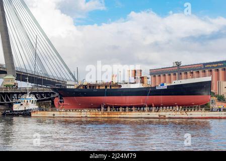 30 mars 2022, Glebe Island Bridge, Sydney, Australie : le navire à vapeur côtier de 1927, John Oxley ayant subi des années de restauration et de préservation, est photographié ici sur le chemin d'être finalement renfloué après 21 ans montés sur un ponton aux ateliers de la Sydney Heritage Fleet à Roselle Bay. Après avoir facilement dégagé l'immense pont ANZAC en béton, le ponton passe par l'ouverture de l'ancien pont Glebe Island sur son chemin vers un quai sec à Garden Island, plus loin en bas du port de Sydney où il sera soigneusement rénové et testé. Banque D'Images