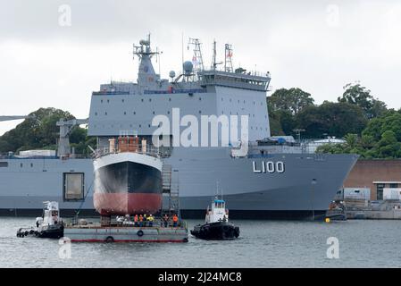 30 mars 2022, Garden Island, Sydney, Australie : le navire à vapeur côtier de 1927, John Oxley ayant subi 21 ans de restauration et de préservation, monté sur un ponton flottant aux ateliers de la Sydney Heritage Fleet, est photographié ici à côté du navire d'atterrissage naval, HMAS Choules, Il est manœuvré en vue d'entrer dans le quai sec de Garden Island pour se replier. Banque D'Images