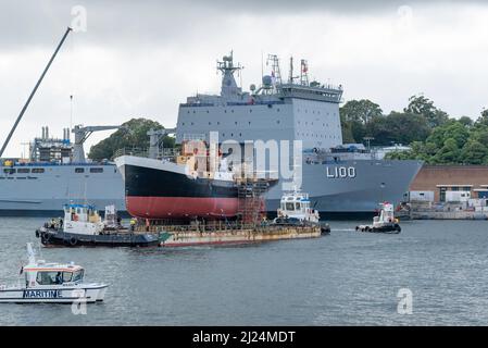 30 mars 2022, Garden Island, Sydney, Australie : le navire à vapeur côtier de 1927, John Oxley ayant subi 21 ans de restauration et de préservation, monté sur un ponton flottant aux ateliers de la Sydney Heritage Fleet, est photographié ici à côté du navire d'atterrissage naval, HMAS Choules, Il est manœuvré en vue d'entrer dans le quai sec de Garden Island pour se replier. Banque D'Images