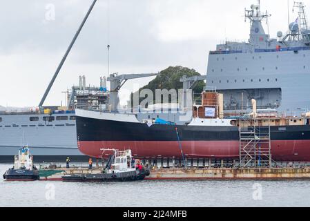 30 mars 2022, Garden Island, Sydney, Australie : le navire à vapeur côtier de 1927, John Oxley ayant subi 21 ans de restauration et de préservation, monté sur un ponton flottant aux ateliers de la Sydney Heritage Fleet, est photographié ici à côté du navire d'atterrissage naval, HMAS Choules, Il est manœuvré en vue d'entrer dans le quai sec de Garden Island pour se replier. Banque D'Images