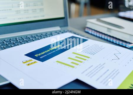 Documents financiers avec des statistiques et des informations sur les bénéfices sur le clavier de l'ordinateur portable avec des données analysées à l'écran sur le lieu de travail de comptable Banque D'Images