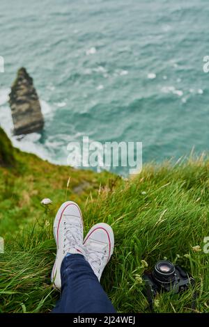 La vue est meilleure d'en haut. Photo en grand angle d'une femme méconnaissable assise sur une falaise et admirant la vue. Banque D'Images