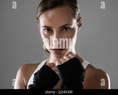 Pas de coups de poing de traction quand il s'agit de faire de l'effort. Photo courte d'une jeune femme attrayante debout dans une position de boxeur. Banque D'Images