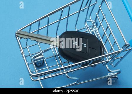 Clé de voiture dans un panier sur fond bleu. Banque D'Images