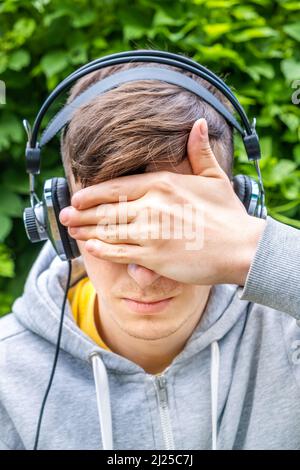 Jeune homme dans un casque couvrez les yeux avec la main à l'extérieur Banque D'Images