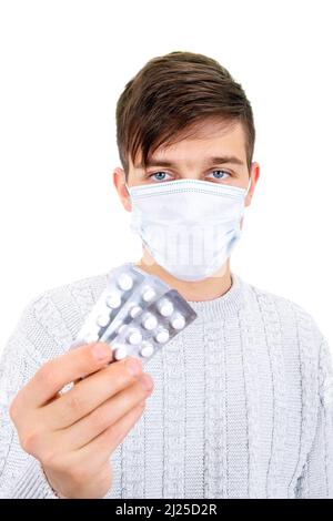 Jeune homme dans le masque de grippe montrer une pilule sur le fond blanc gros plan Banque D'Images